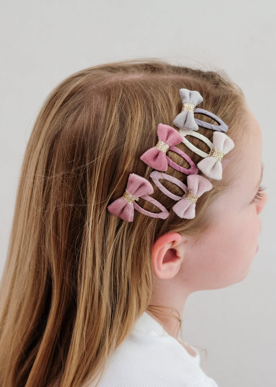 Girl with pastel bow hair clips in her hair on a plain background