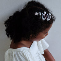 Young girl wearing a white blouse with a decorative headband against a plain background