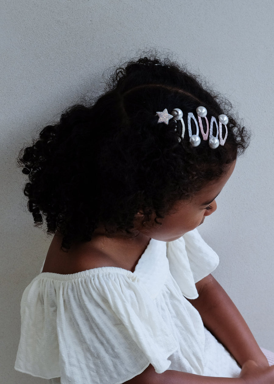 Young girl wearing a white blouse with a decorative headband against a plain background