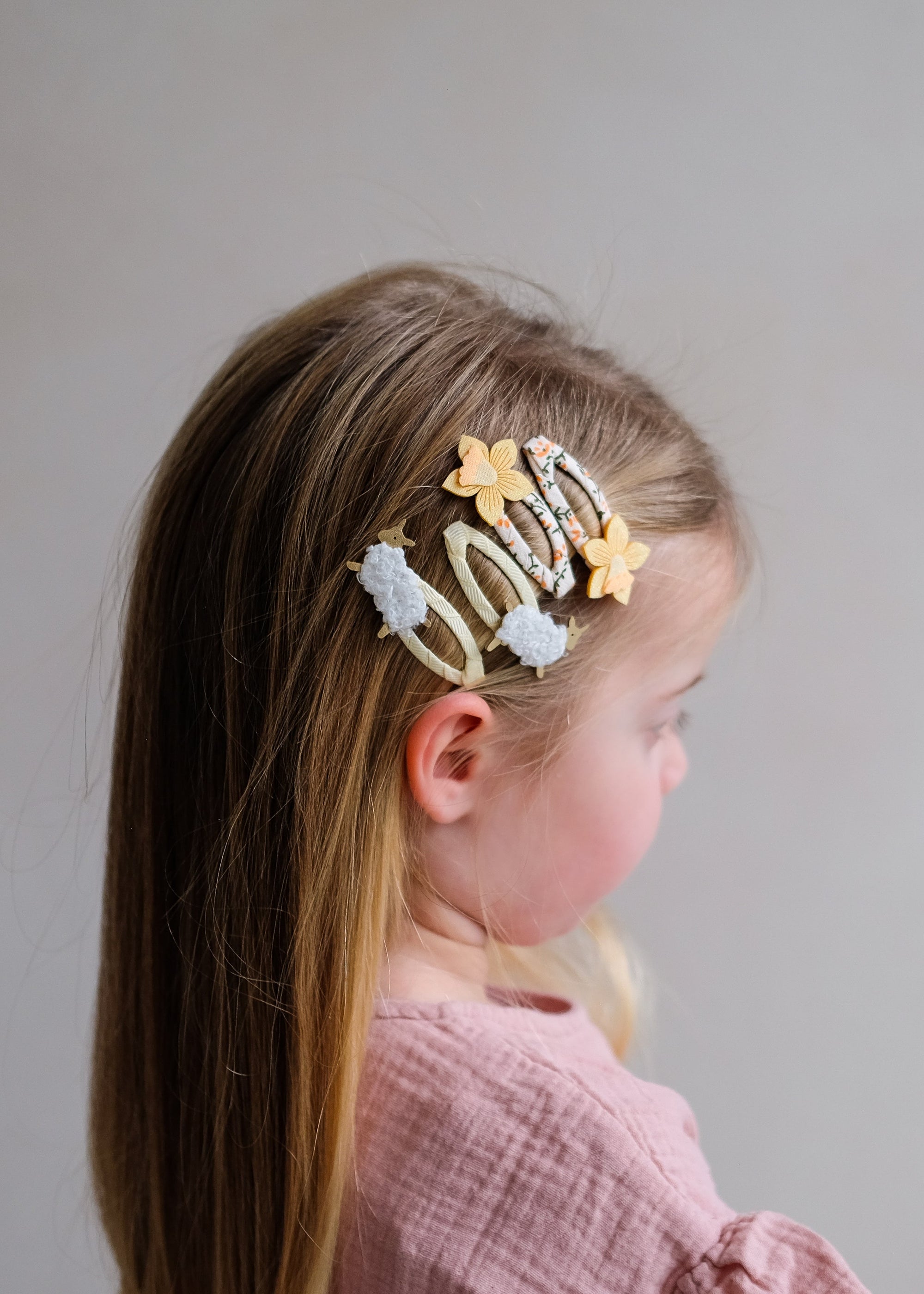 Child with decorative hair clips on a plain background