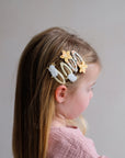 Child with decorative hair clips on a plain background
