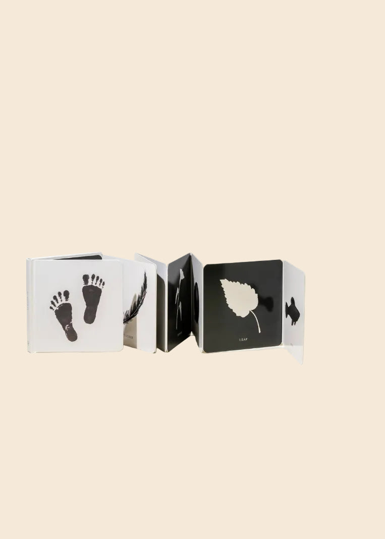 Book with black and white illustrations of footprints, a leaf, and other shapes on a beige background