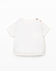 White t-shirt with a small graphic on a light beige background