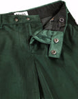 Close-up of dark green corduroy trousers showing the waistband, button details, and inner lining.