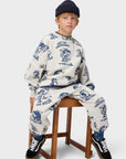 Child wearing a patterned outfit sitting on a stool against a white background