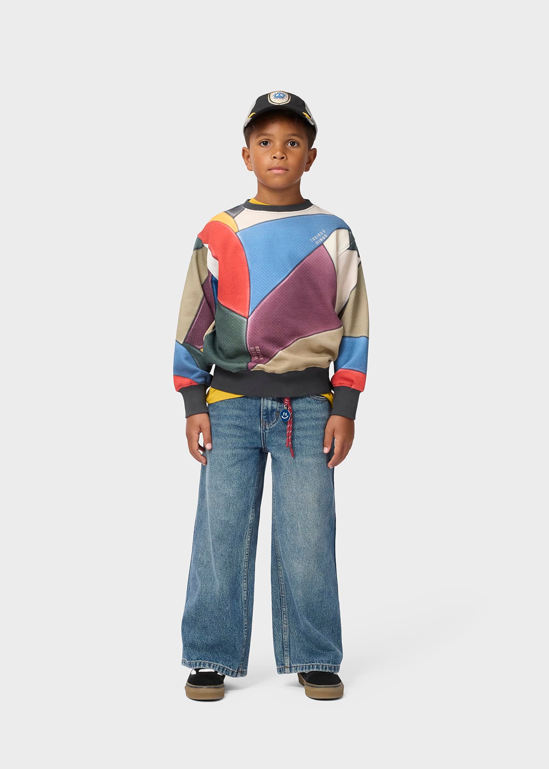 Child wearing a colorful sweater and jeans on a white background