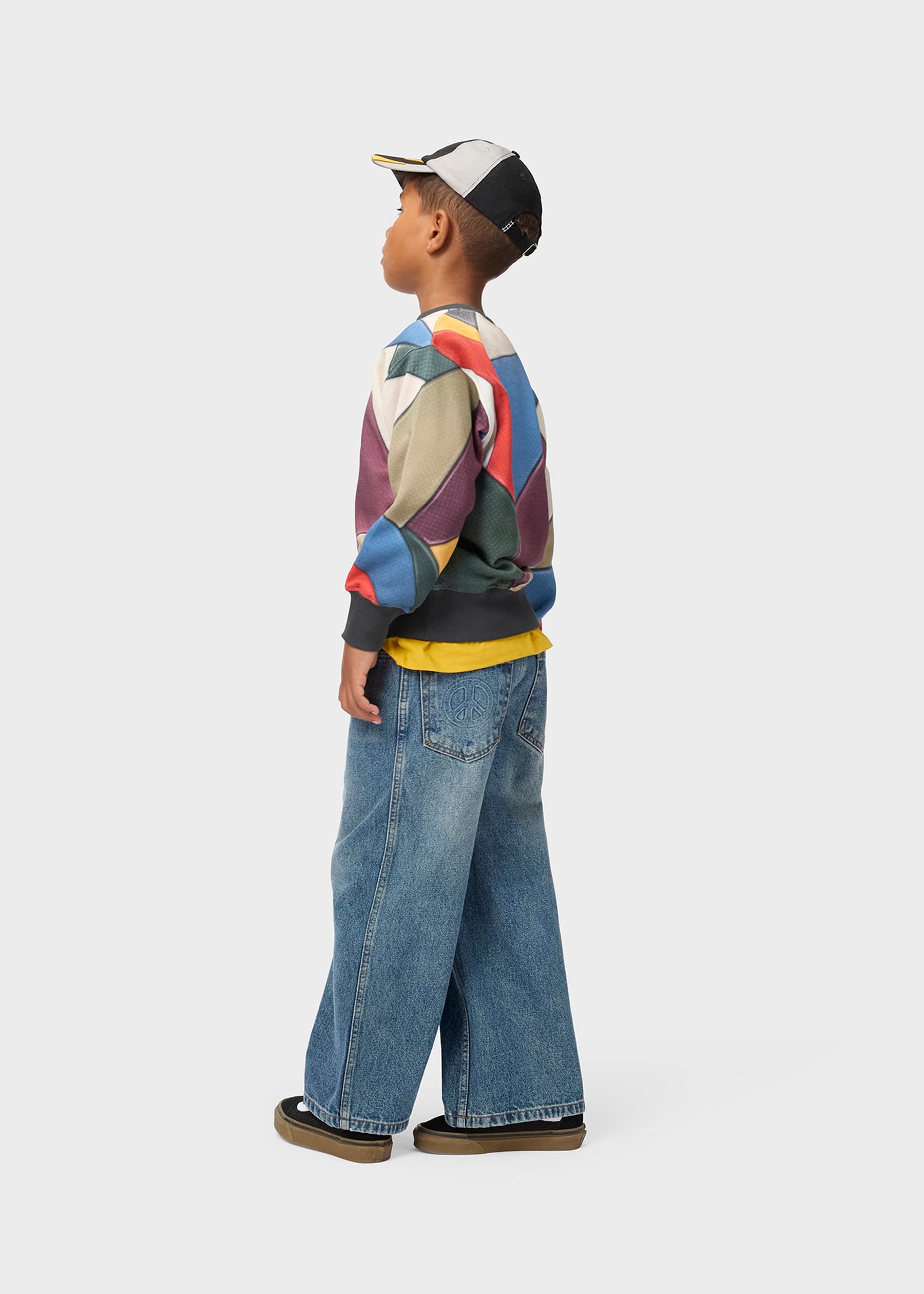 Child wearing a colorful jacket and jeans on a white background
