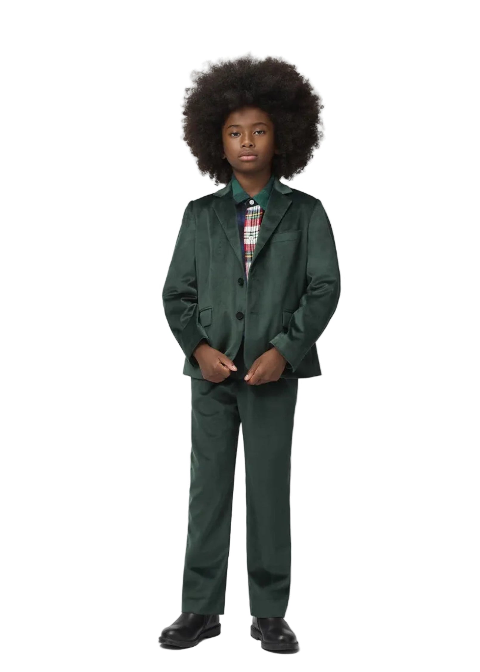 A child model wearing a dark green two-piece suit with a patterned shirt and tie, standing against a light gray studio background.