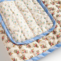 Floral-patterned quilt with blue trim on a white background
