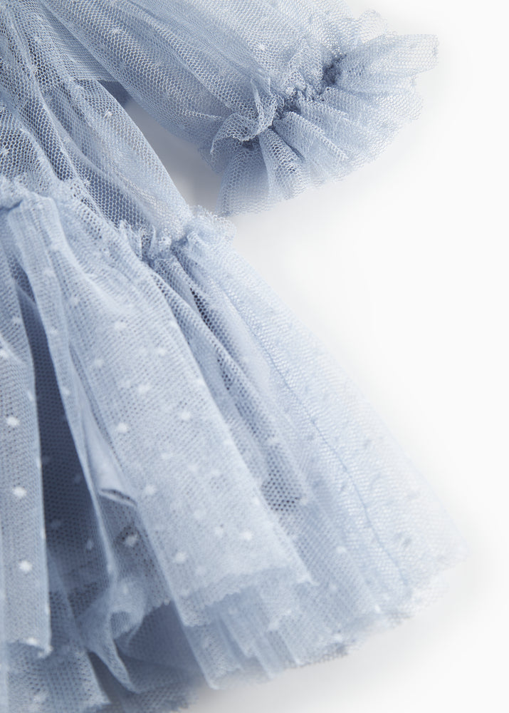 Close-up of a light blue tulle skirt with polka dots on a white background