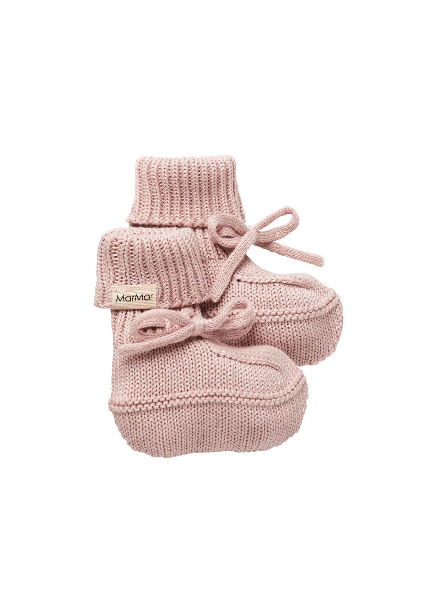 Pair of pink knitted baby booties with a brand label on a white background