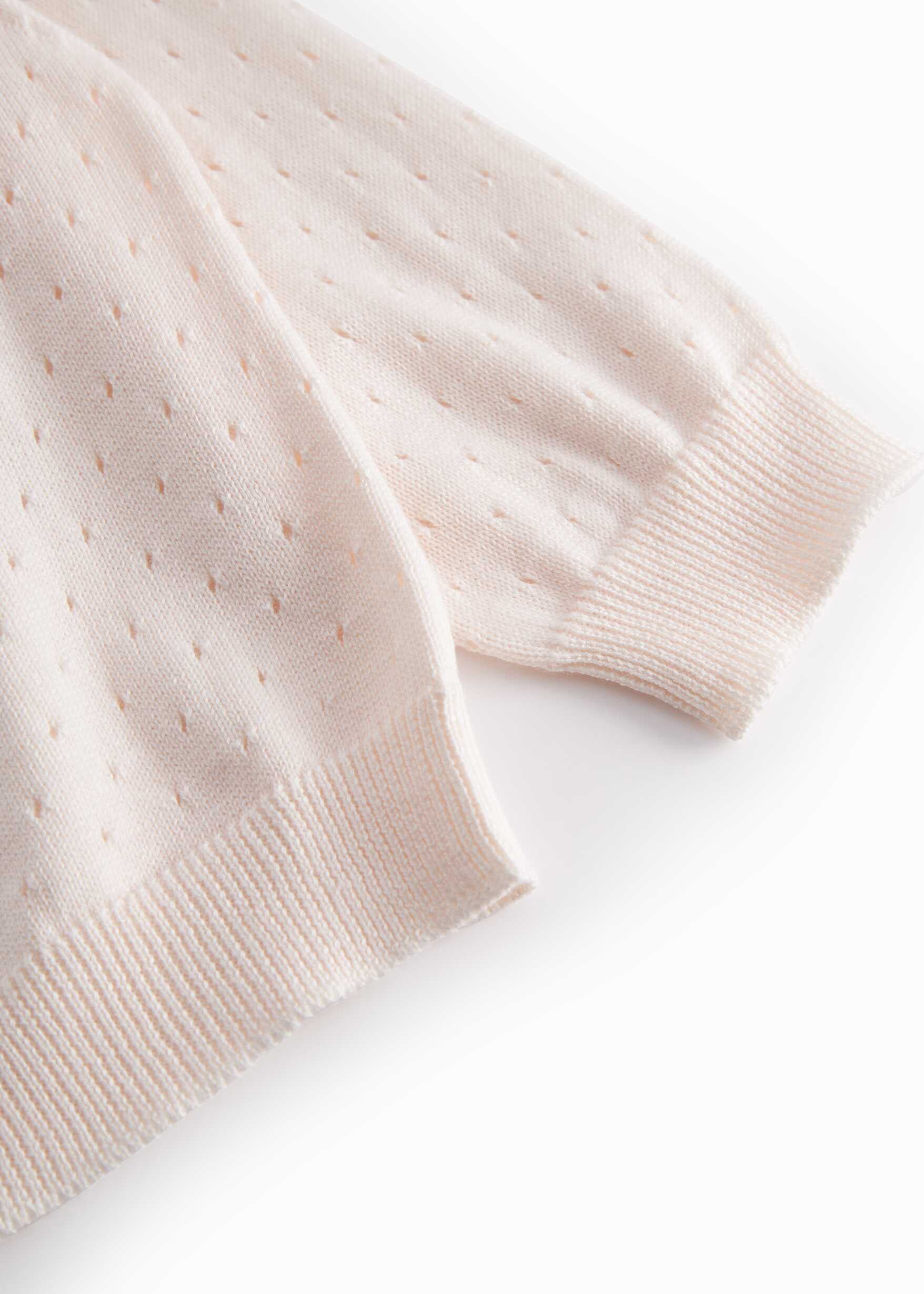 Close-up of a light pink knitted sweater on a white background