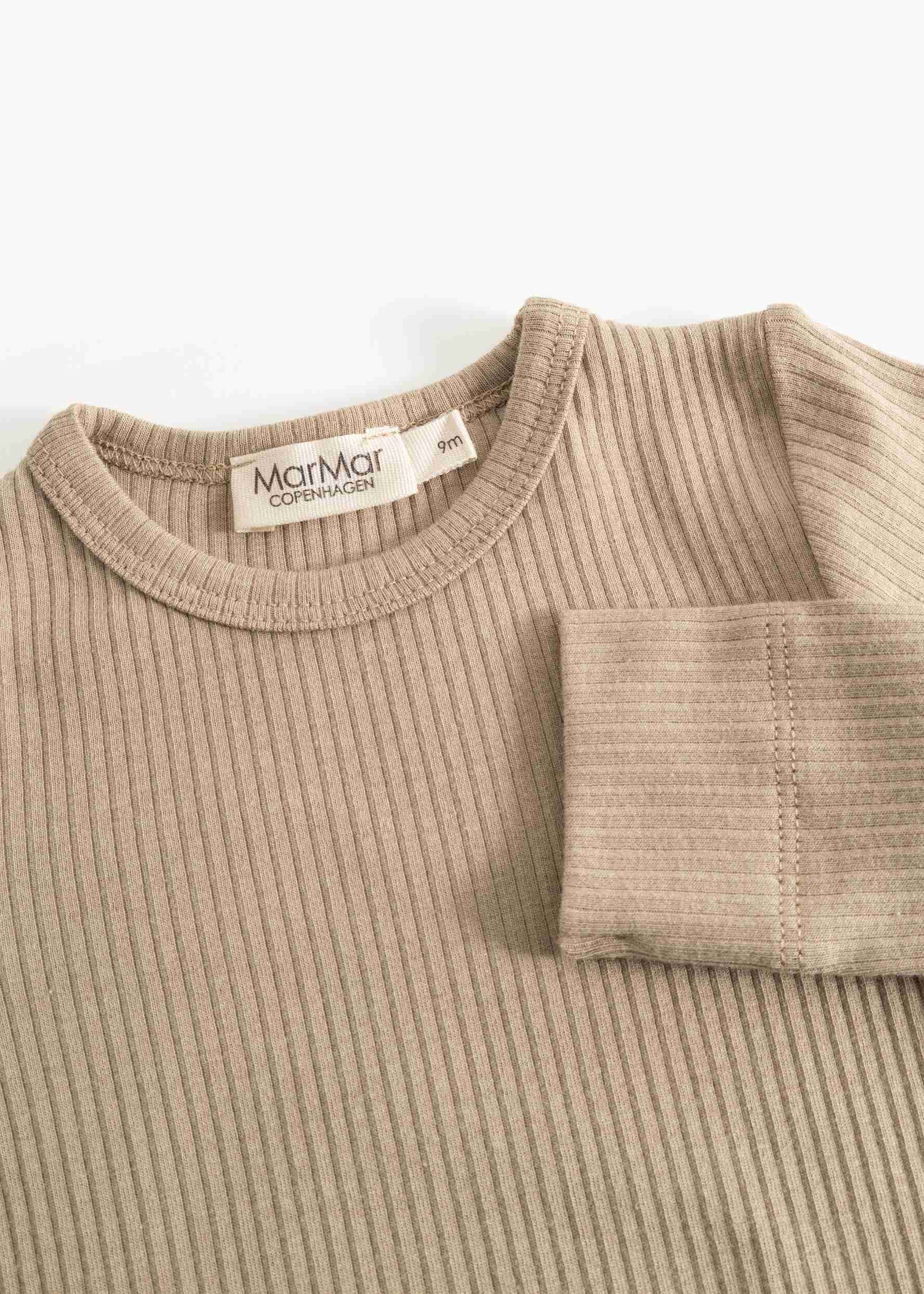 A close-up of a ribbed knit crewneck sweater in a light taupe-beige color, with a folded cuff showing the ribbed texture and a visible MarMar Copenhagen brand label.