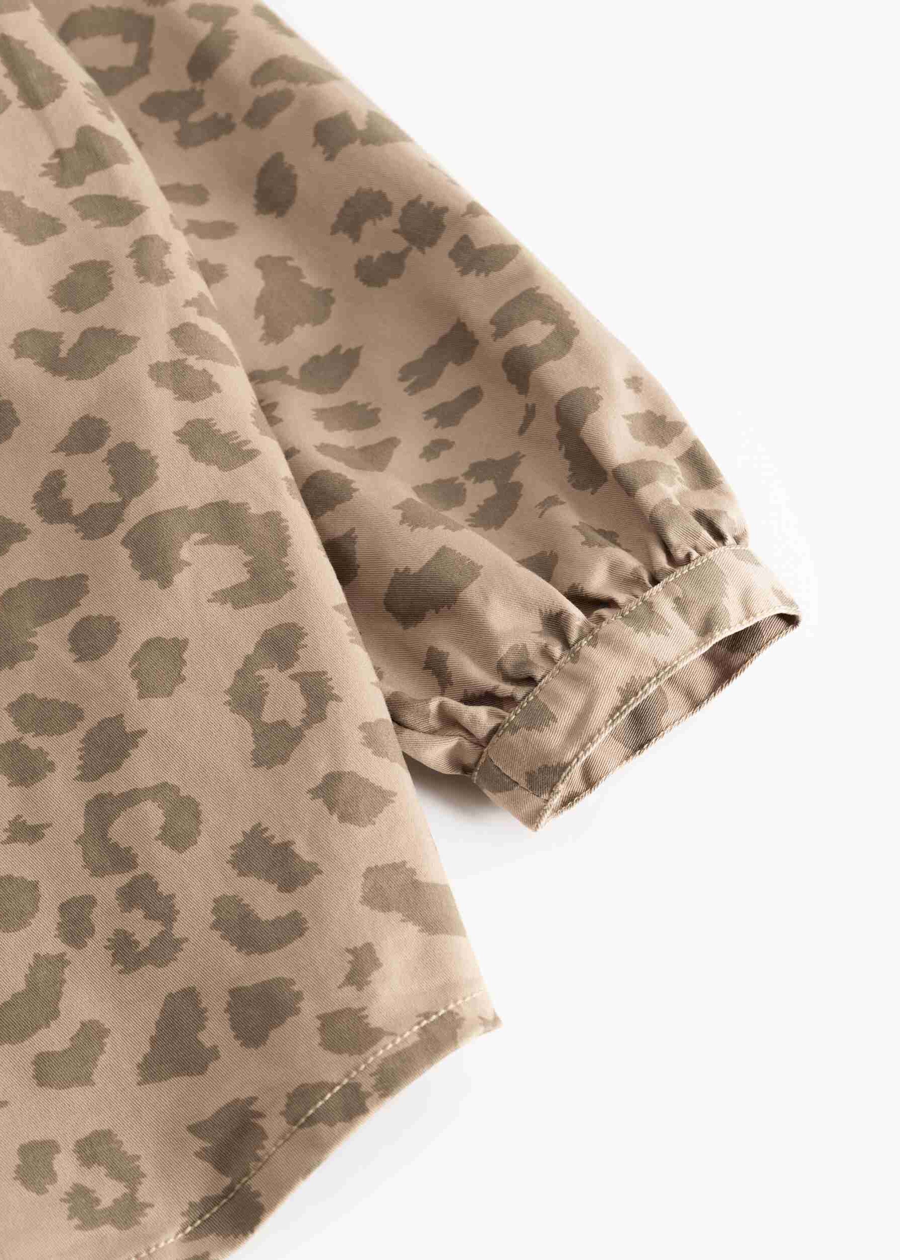 Close-up of a beige and olive green leopard print fabric sleeve with a gathered elastic cuff, shown on a plain white background.