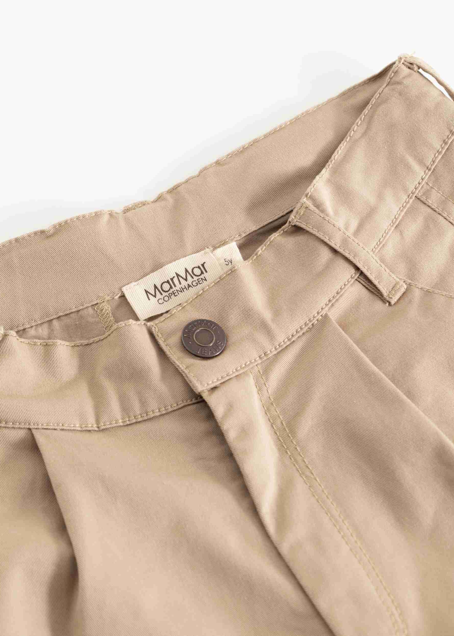 Close-up of a pair of beige trousers showing the waistband, belt loops, button closure, and a visible MarMat label.