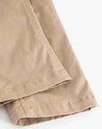Close-up of folded khaki fabric with visible stitching and hem detail on a white background.
