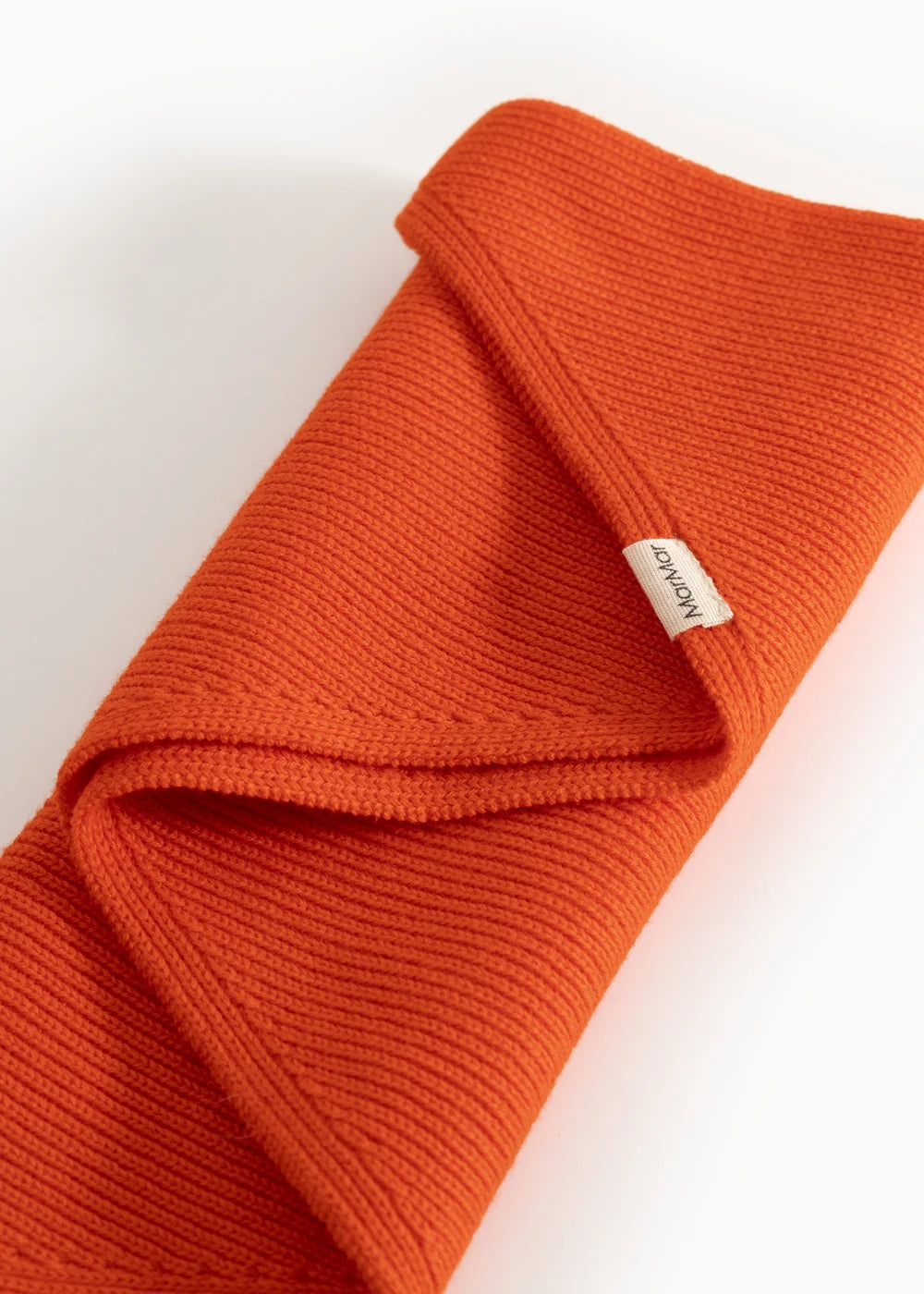 Orange knitted sweater with a brand label on a light background