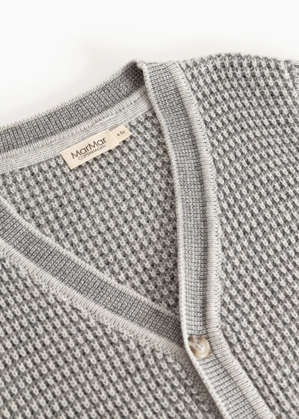 Close-up of a textured gray garment with a brand label on a white background