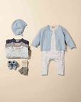 Baby clothing set with cardigan, romper, hat, and socks on a beige background