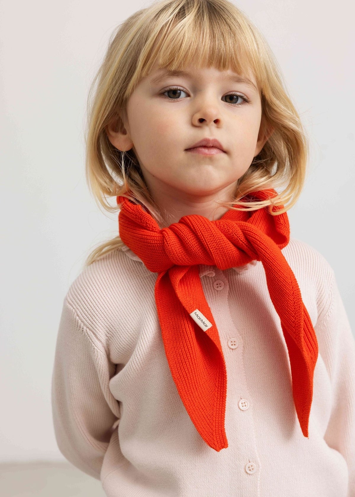 Child wearing a red scarf on a plain background