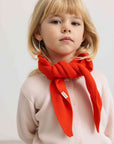 Child wearing a red scarf on a plain background