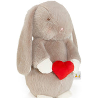 Plush toy rabbit holding a red heart on a white background