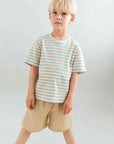 Young boy wearing a striped shirt and shorts against a plain background