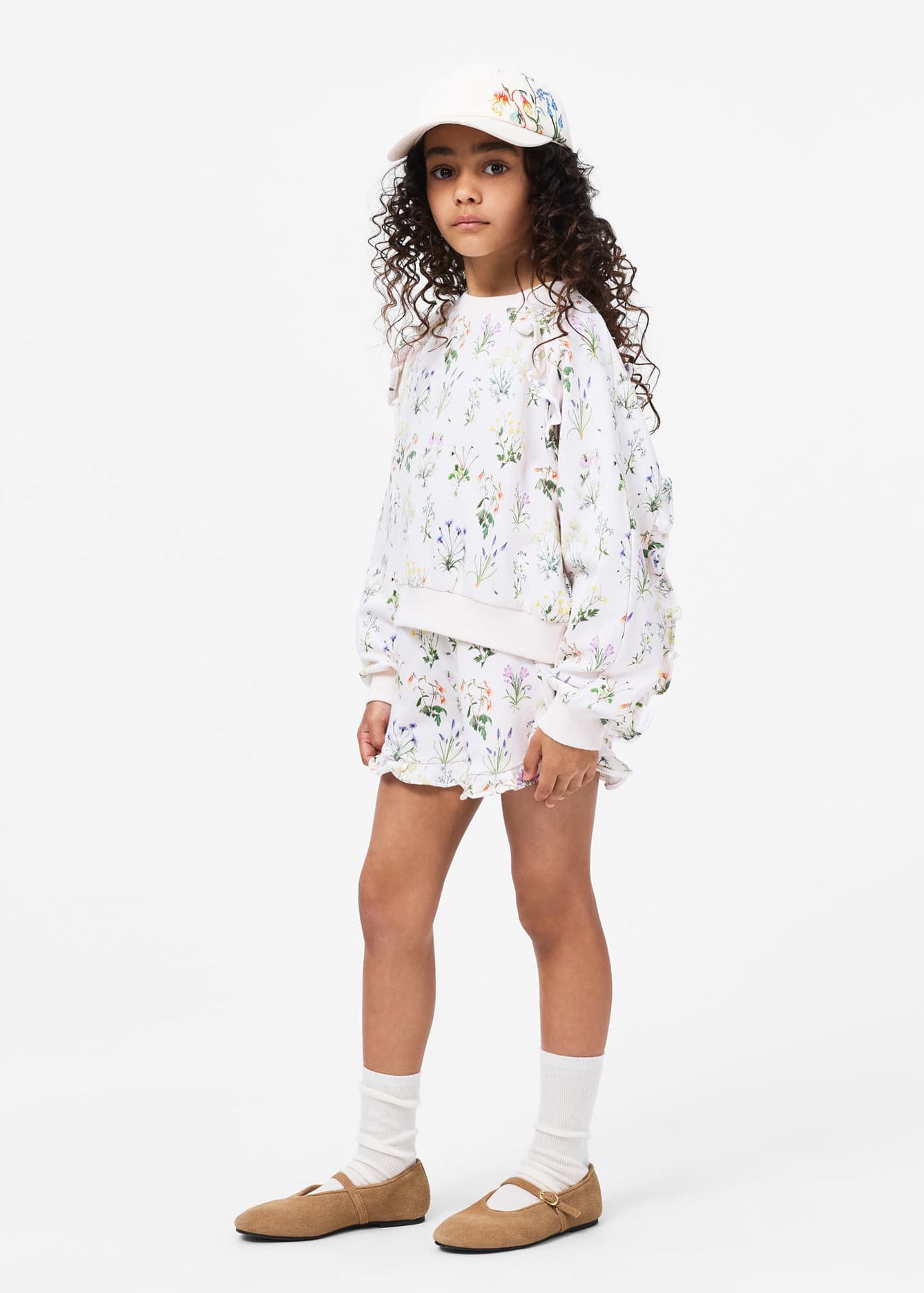Young girl wearing a floral outfit with a white background