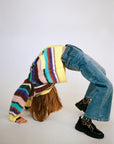 Person wearing a colorful striped sweater and blue jeans on a white background