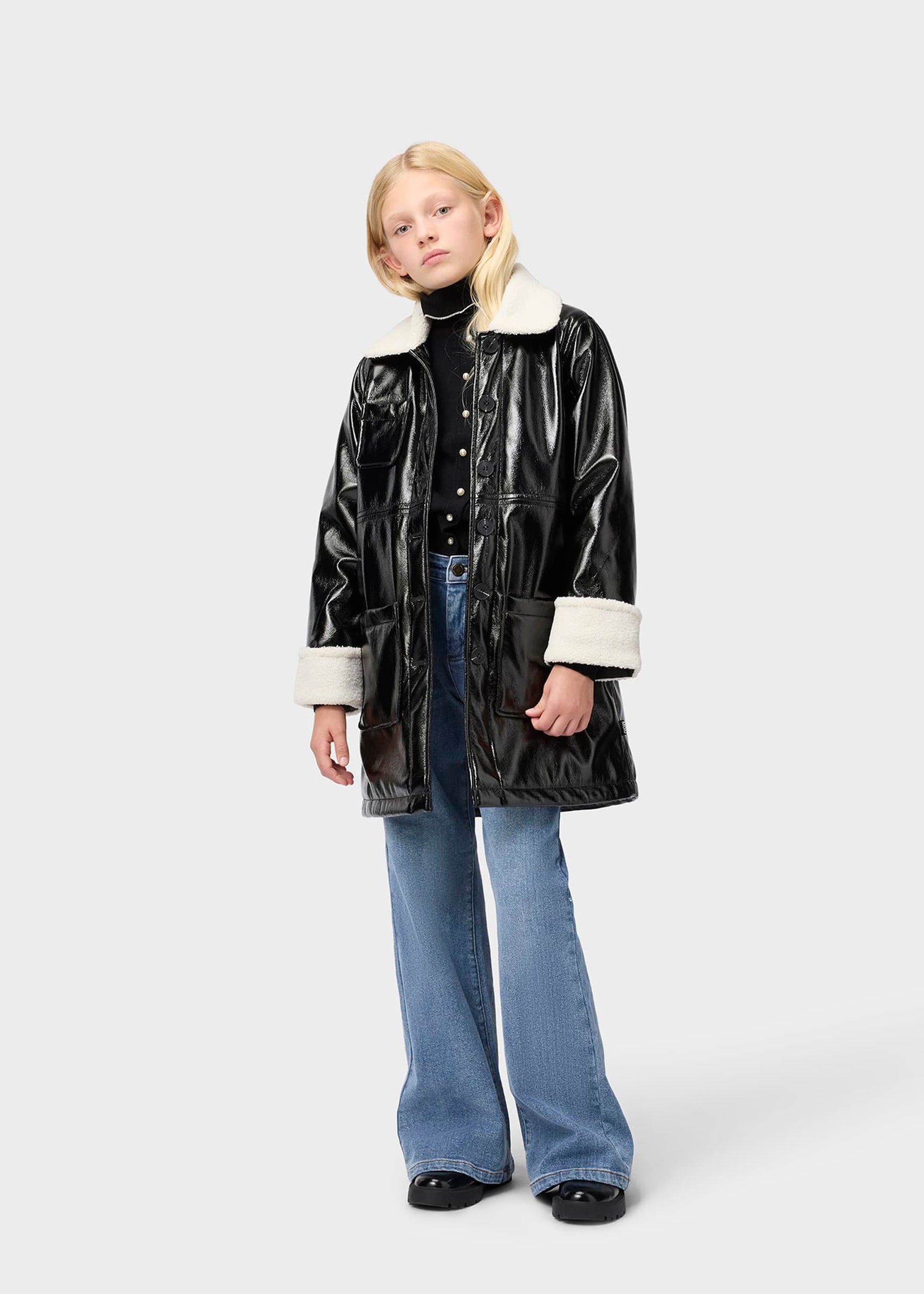 Person wearing a black vinyl jacket with white trim on a white background