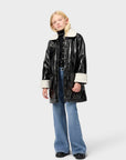 Person wearing a black vinyl jacket with white trim on a white background