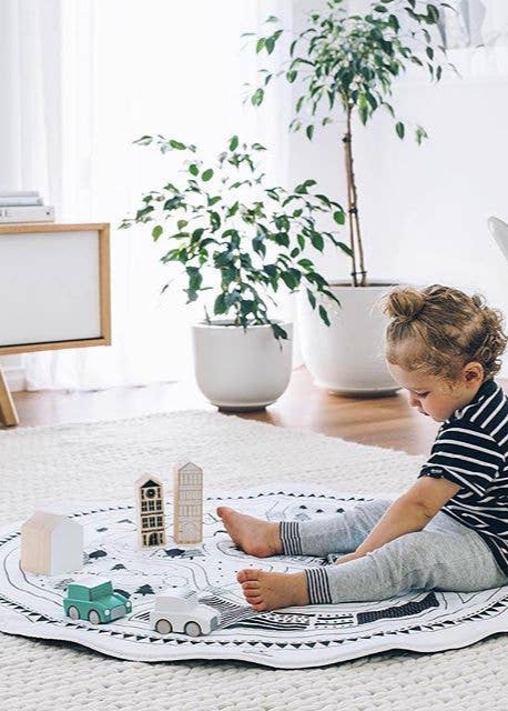 Child playing with toys on a rug in a bright living room