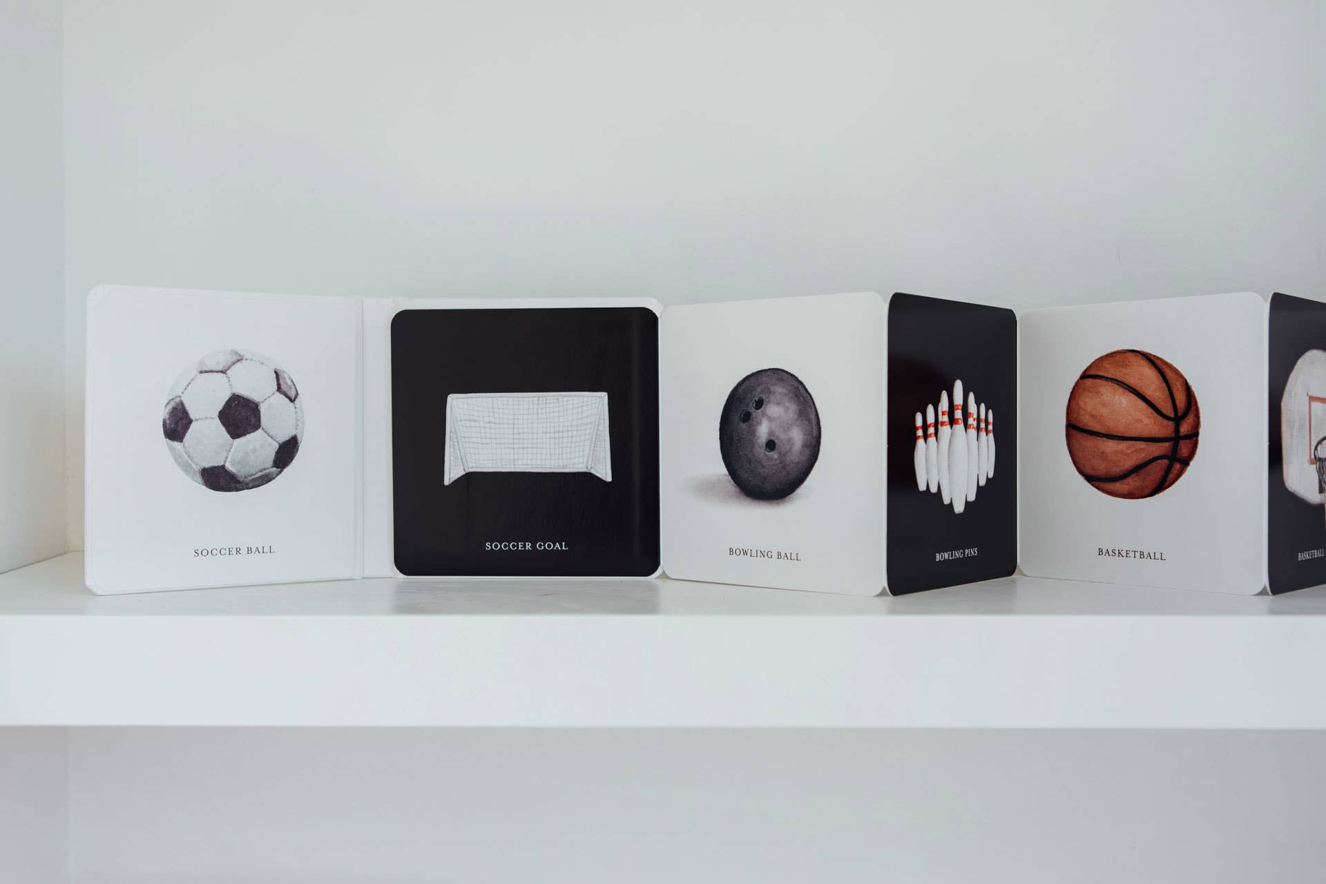 Collection of card decks with sports-themed designs on a white shelf.