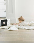 Baby lying on a blanket with educational cards on a wooden floor