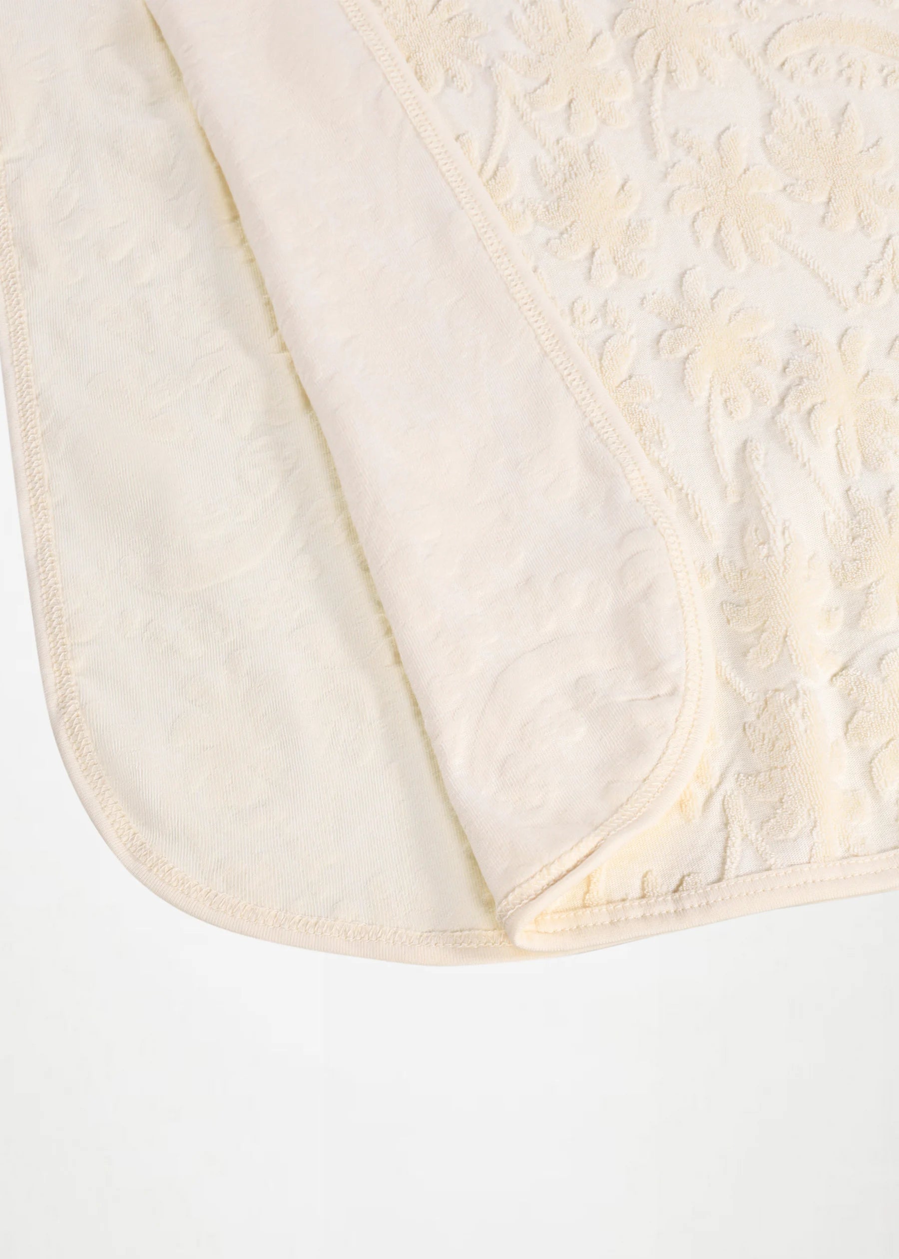 Close-up of a textured white fabric with a subtle pattern on a white background