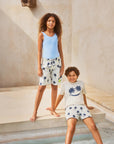 Two children in matching outfits standing by a pool with a neutral background