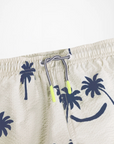Beige swim shorts with navy palm tree pattern on a white background