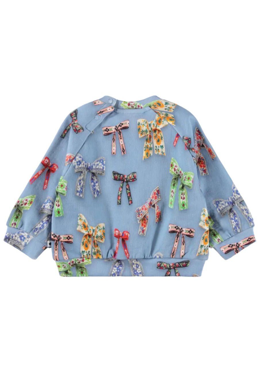 A light blue long-sleeve baby sweater featuring an all-over print of colorful ribbon bows in various floral and patterned designs, shown against a plain white background.