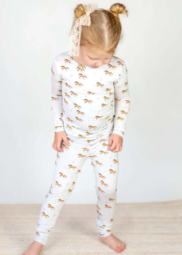 Child wearing a white outfit with gold animal prints on a plain background
