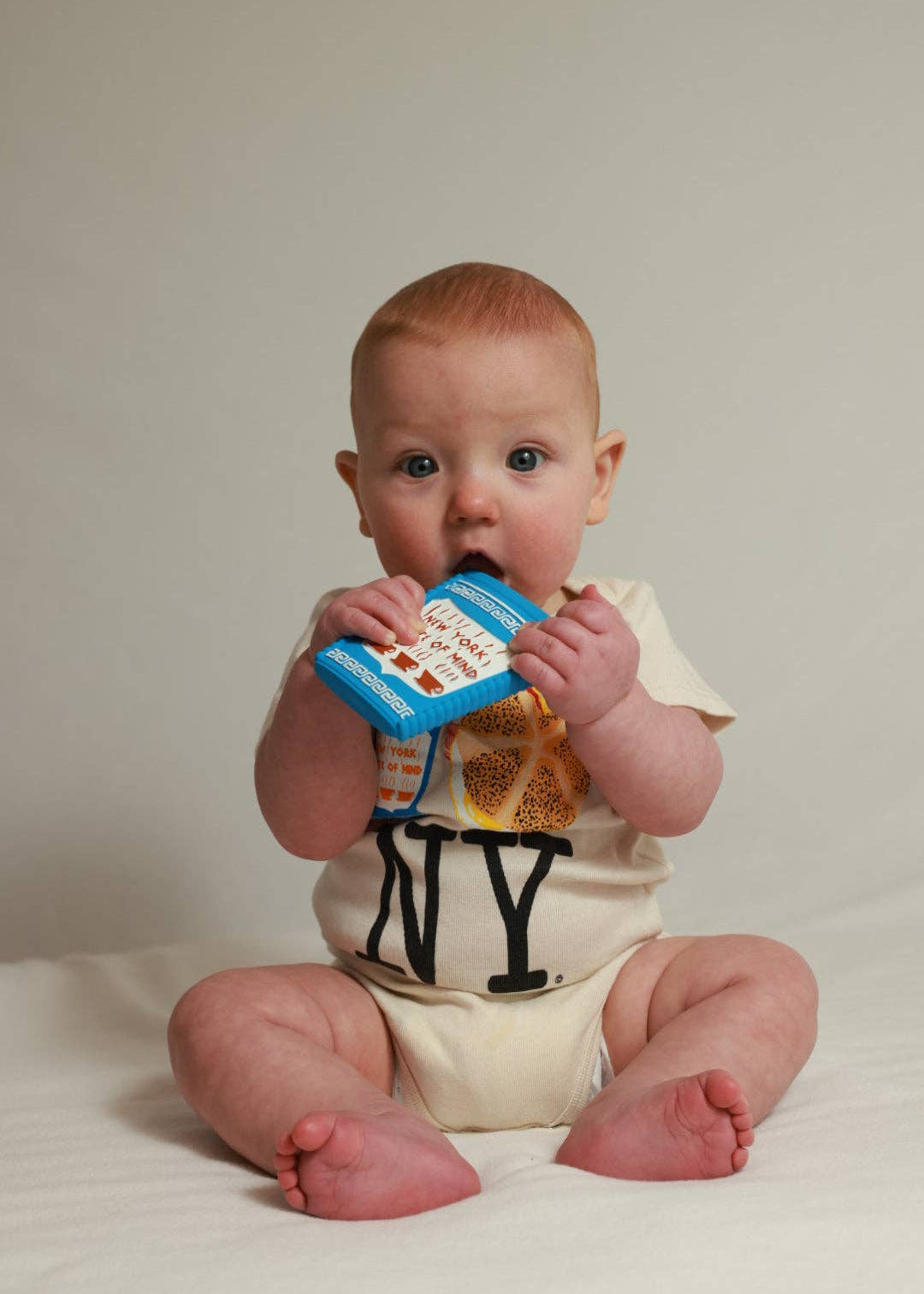 Baby holding a colorful book against a plain background