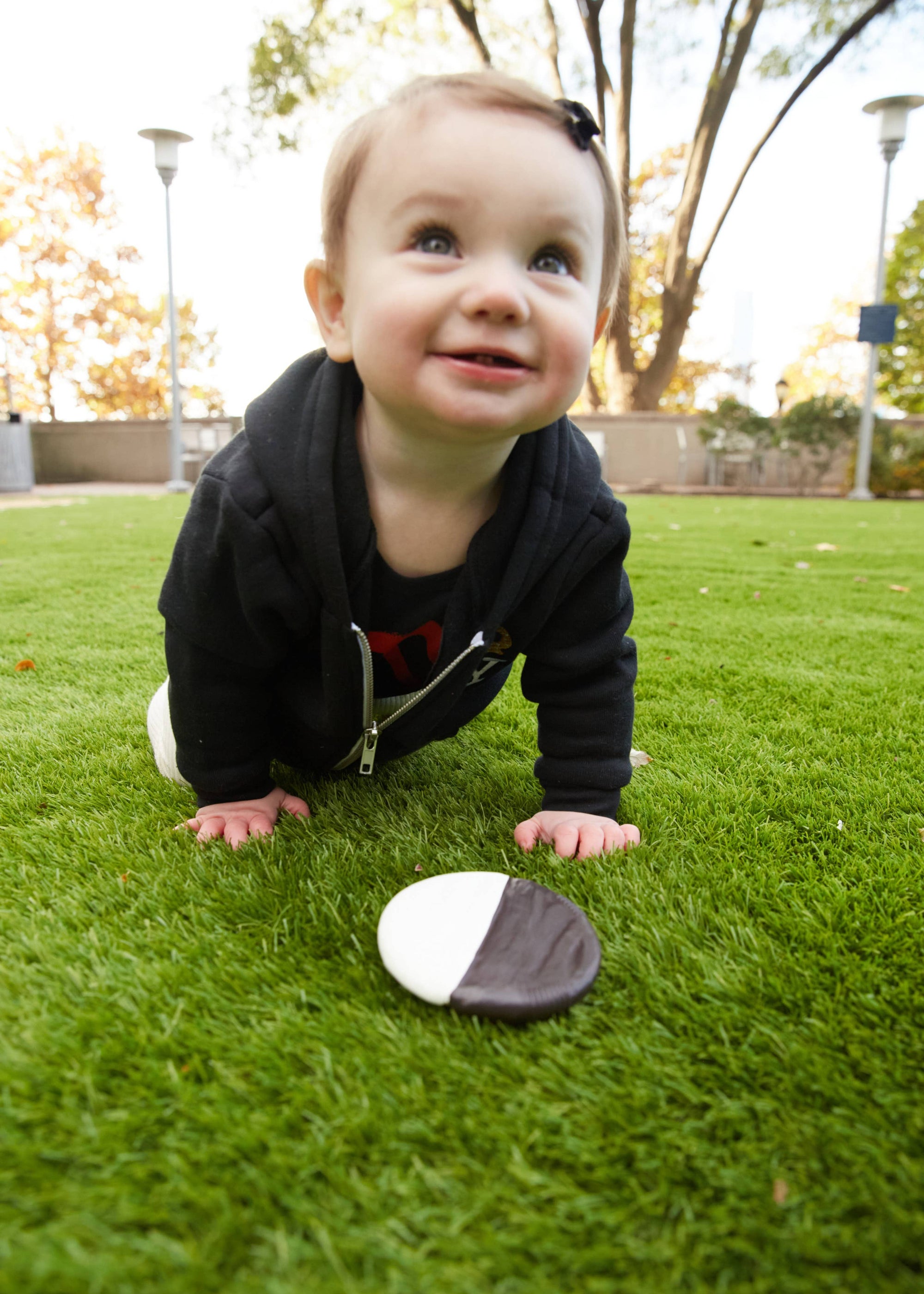 Baby crawling on grass with a rock in front