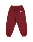 A pair of dark red corduroy jogger pants with an elastic waistband and cuffs, featuring a back pocket with a small white label, shown against a plain white background.