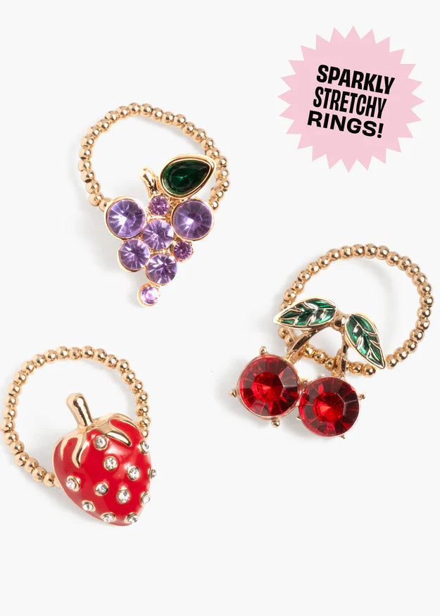 Three sparkly stretchy rings with fruit designs on a white background