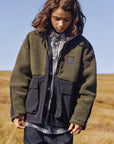 Person wearing a green jacket with black accents in an open field