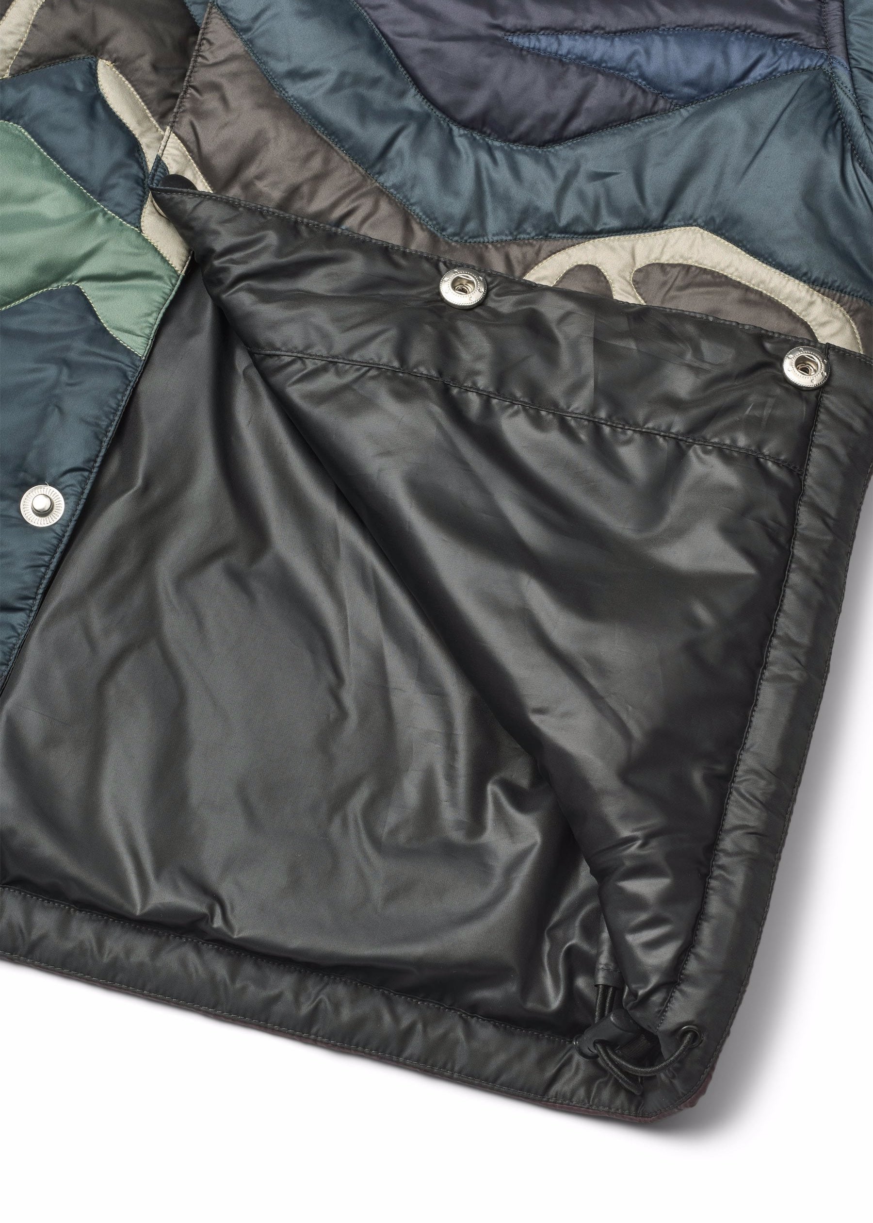 Close-up of a black quilted jacket with visible stitching and buttons on a white background