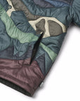 Close-up of a multicolored quilt with green, brown, and gray patterns on a white background.