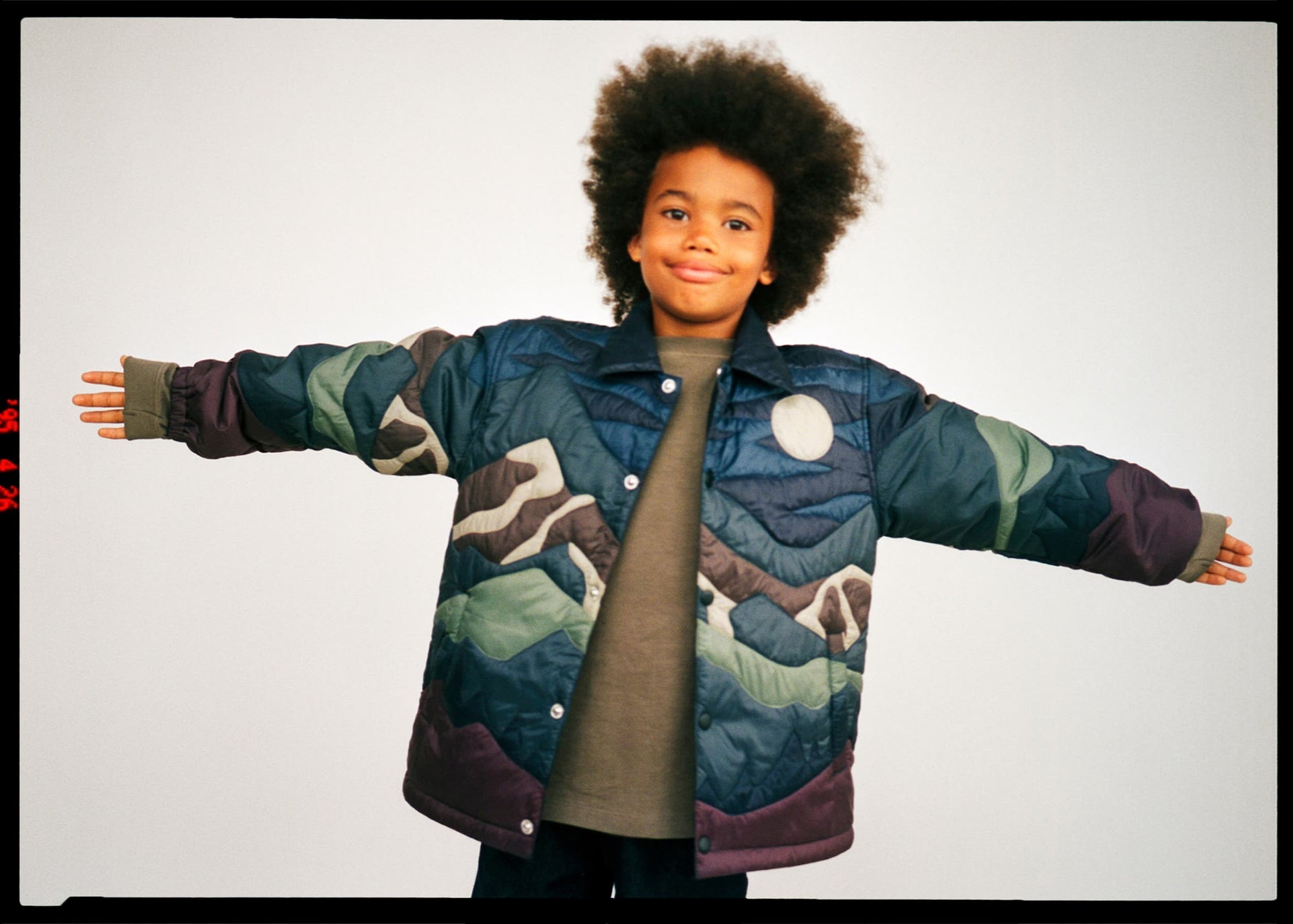 Person wearing a colorful camouflage jacket on a plain background