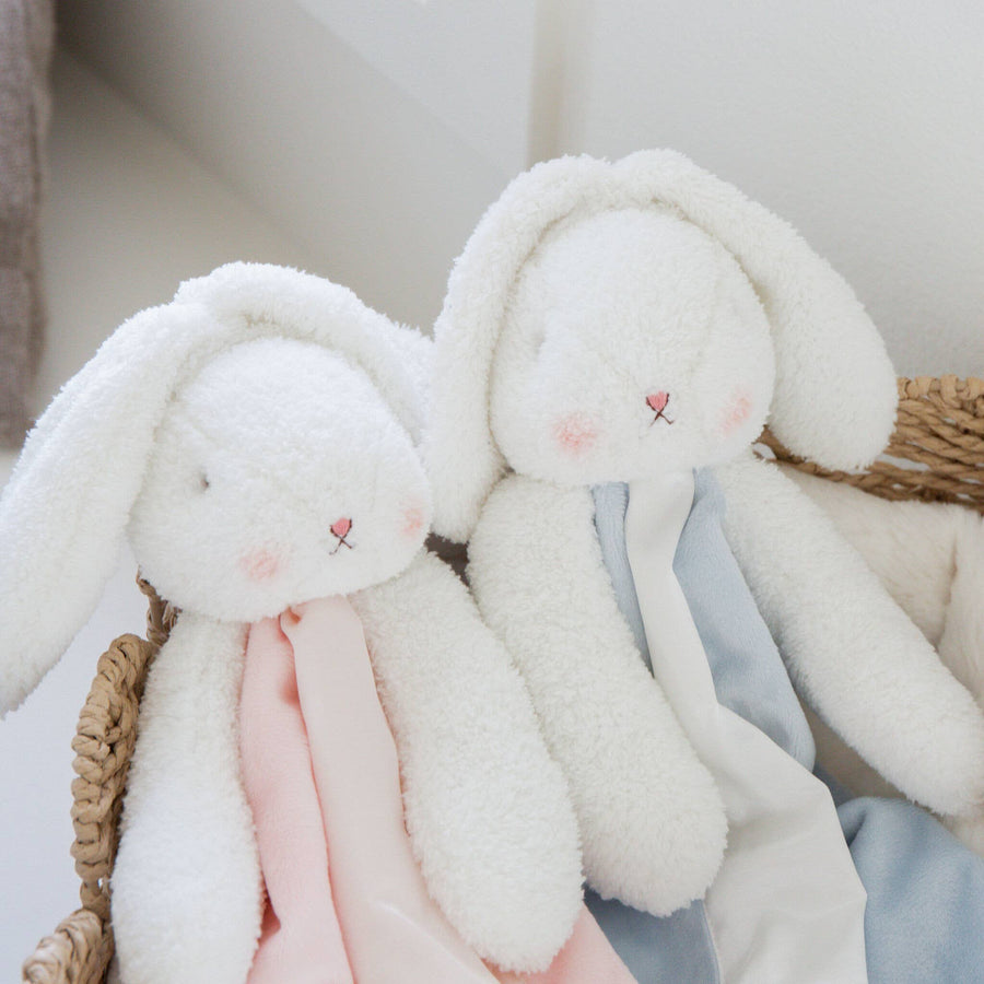 Two plush bunny toys with soft fabrics in a basket