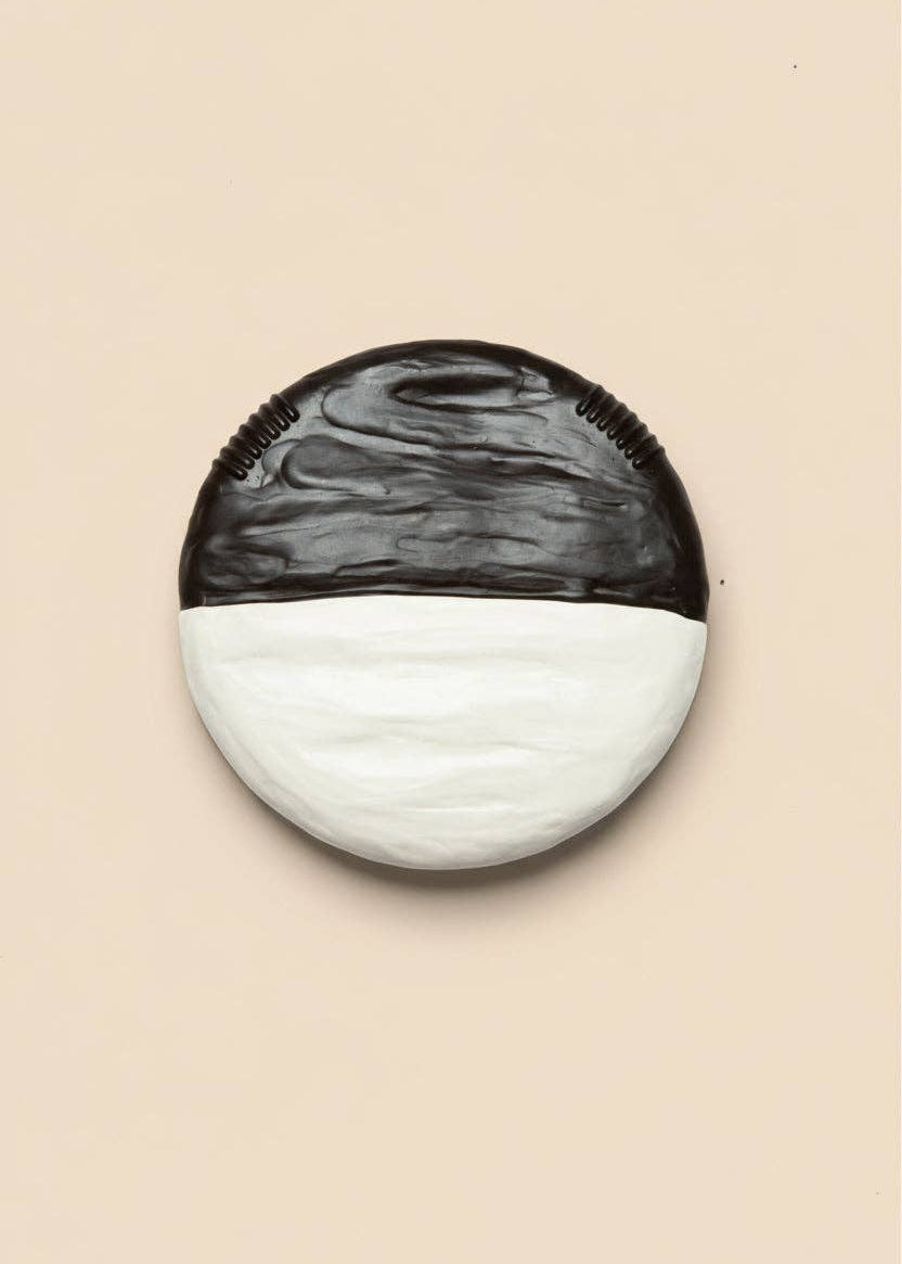 Round wall light fixture with black and white marbled design on a beige background