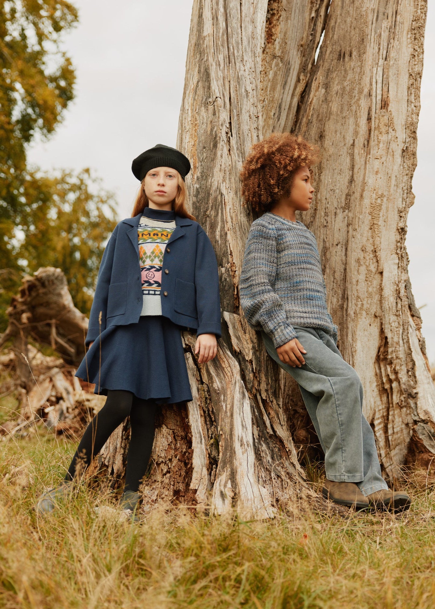 Two children sitting on a tree stump in a natural setting